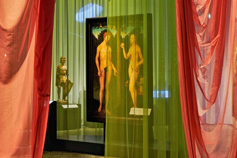 Ein durchlässiger Vorhang verschleiert die Sicht auf ein Porträt eines nackten Paares.