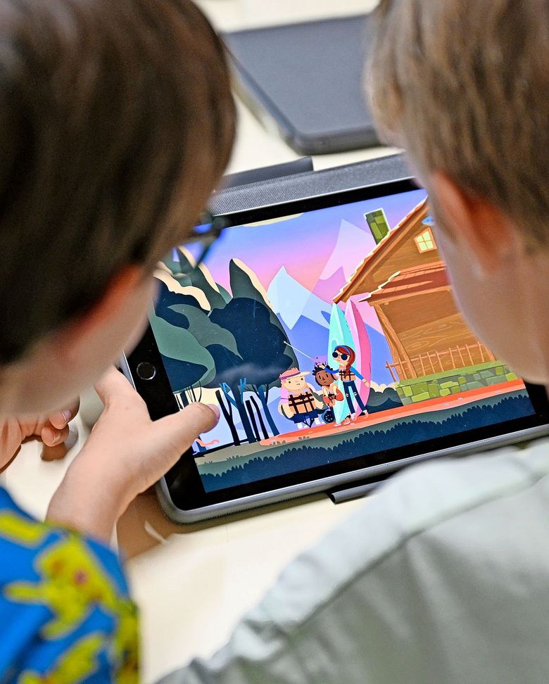 Zwei Schüler sitzen vor einem Tablet, das das Spiel «The Unstoppables» zeigt.