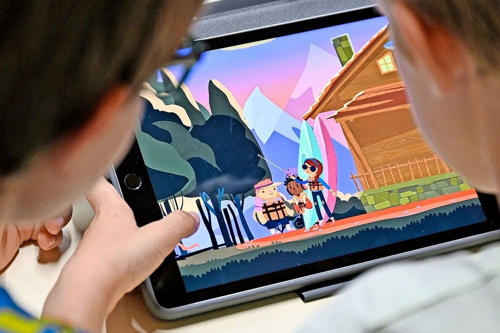 Zwei Schüler sitzen vor einem Tablet, das das Spiel «The Unstoppables» zeigt.