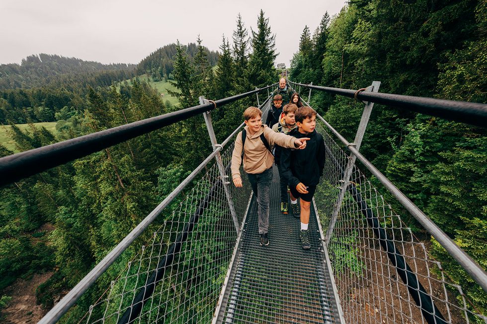 Kinder gehen über eine Hängebrücke.
