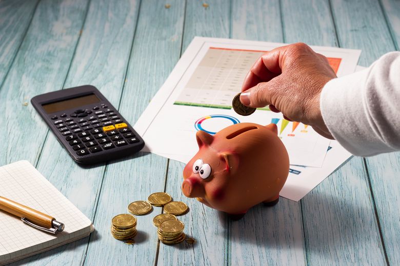 1467667739 Frau wirft Geld in ein Sparschwein.