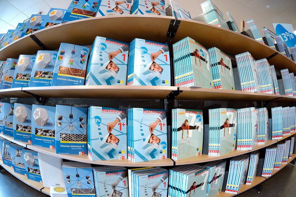 Ein Regal mit Schulbüchern, die mehrheitlich blau gefärbt sind.