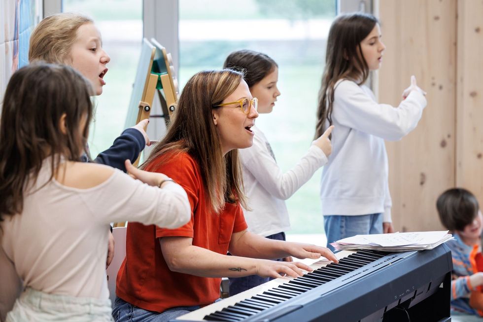 Reportage Tagesschule Prêles Eine Lehrerin und ihre Tagesschulkinder singen zusammen ein Lied.