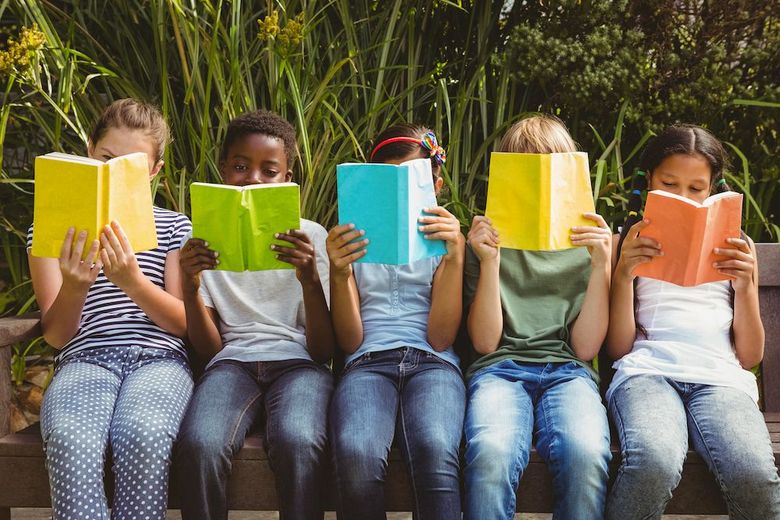 Lesende Kinder sitzen auf einer Mauer.