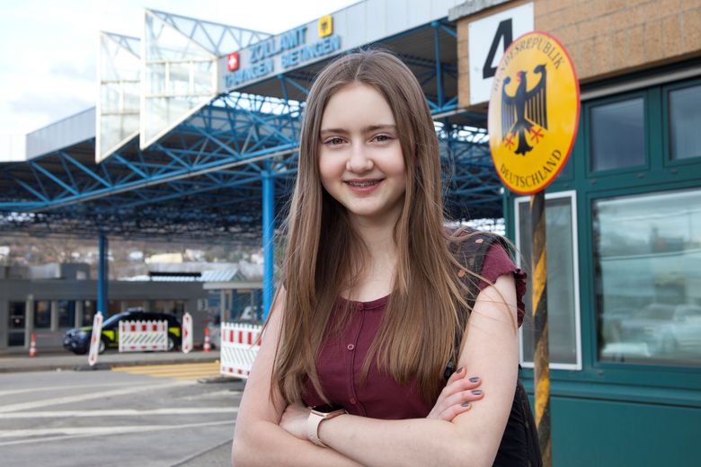 Junge Frau steht vor einem Grenzübergang.