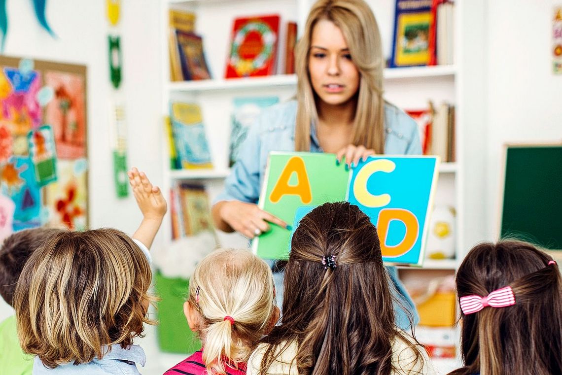 504988272 Lehrerin bringt Kindern das Alphabet bei.