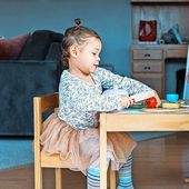 1456068489 Kind sitzt am Tisch.