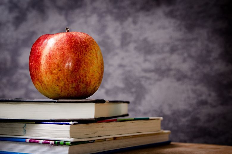 Ein Apfel liegt auf einem Stapel Bücher.